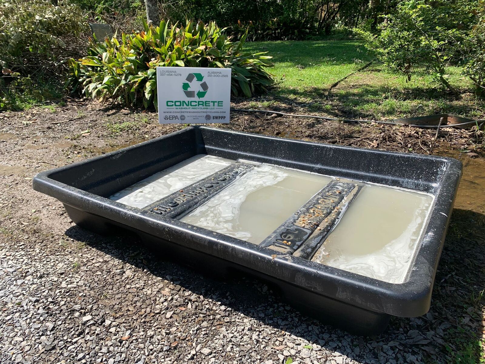 A washout basin holding grey concrete wash water on a job site